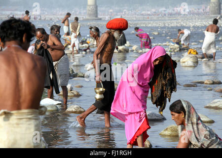 Mann mit roten Turban trägt eine Kanne im heiligen Wasser des Ganges während Kumbh mela in Haridwar, Indien Stockfoto