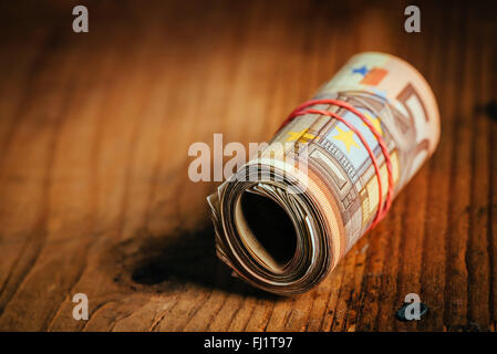 Konzept Geld sparen bares Geld mit Gummiband auf hölzernen Schreibtisch, fünfzig Euro Banknoten persönliche Haushaltsbudget Stack aufgerollt Stockfoto