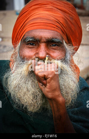 Mann mit Bart und Turban rauchen Beedi in Varanasi, Indien Stockfoto