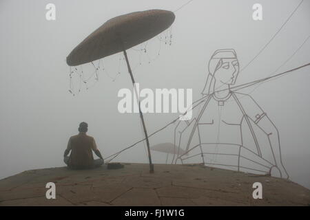 Mann, der betet im Nebel im Winter an Ghat von Varanasi, Indien Stockfoto