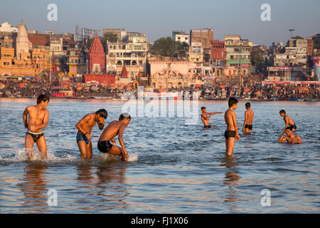 Junge Männer spielen im heiligen Wasser des Ganges in Varanasi Stockfoto