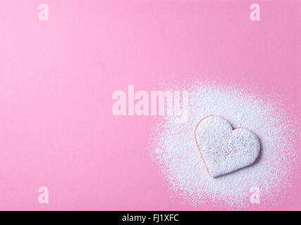 Herzförmige Cookie mit Zuckerguss auf rosa Papierhintergrund Stockfoto