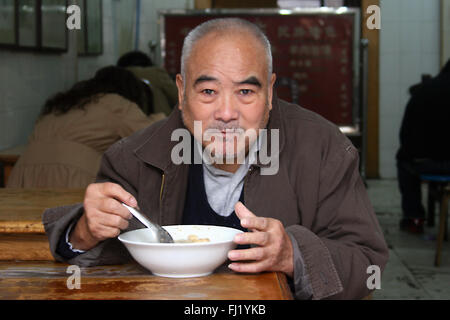 Alter Mann essen Suppe in Hutong Gegend, Peking, China Stockfoto