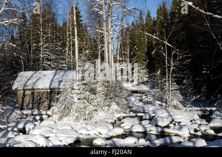 Ein altes Fachwerkhaus Ferienhaus in der Nähe von einem kleinen Fluss in Winterlandschaft,, aus Nordschweden. Stockfoto
