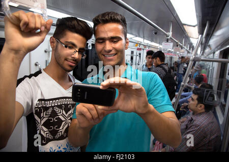 Zwei junge Männer sind unter selfie mit Handy in der U-Bahn von Teheran, Iran Stockfoto