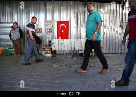 Männer gehen in den Straßen von Istanbul mit Türkische nationale Flagge an der Wand Stockfoto