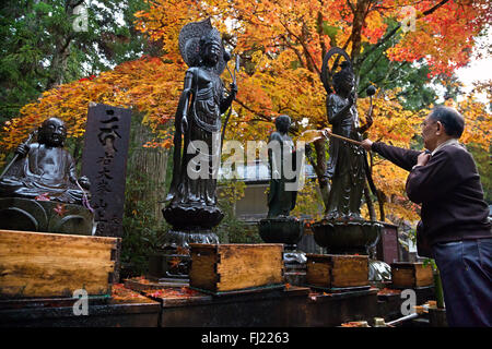 Man gießt Wasser auf buddhistischen Statuen in Okunoin Friedhof, Koyasan Stockfoto