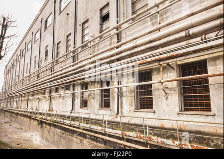 Alte Rohre an der Wand außerhalb einer alten verlassenen Fabrik. Stockfoto