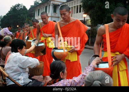 Tak Bat Ritual - Buddhistische Mönche erhalten Reis und Lebensmittel aus pupulation am frühen Morgen in Luang Prabang, Laos, Asien Stockfoto