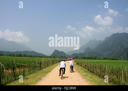 Zwei Menschen Radfahren in der typischen Landschaft rund um das Dorf Vang Vieng, Laos, Südostasien Stockfoto