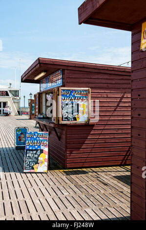 Helles Sonnenlicht betont die Werbung auf Brettern außerhalb einer hölzernen Stall zu verkaufen heiße frische Donuts auf Paignton Pier gelegen Stockfoto