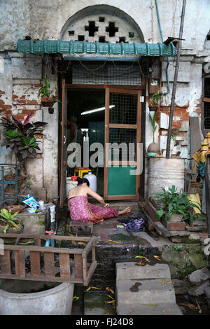 Frau waschen bei Eingang ihres Hauses in Mandalay, Myanmar Stockfoto