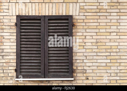 Alte Fenster mit hölzernen Fensterläden in Ziegelmauer Hintergrundtextur Foto Stockfoto