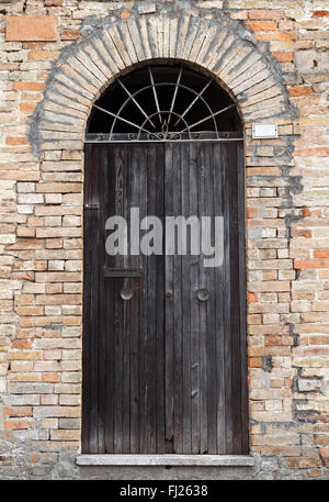 Schwarzen Holztür mit Bogen in alten Steinmauer, Foto Hintergrundtextur Stockfoto