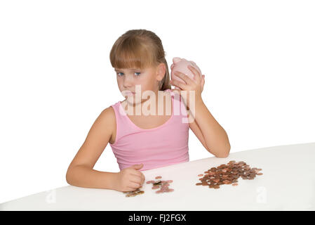 Mädchen mit Sparschwein und Euro-Münzen auf dem Tisch, isoliert Stockfoto