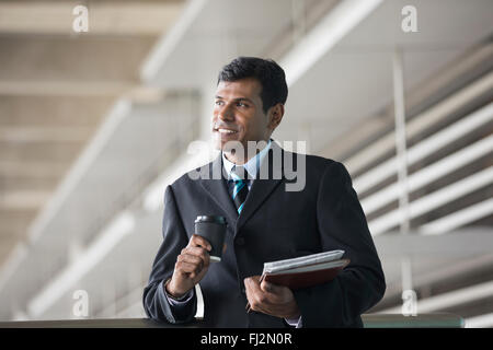 Porträt von ein indischer Geschäftsmann vor modernen Bürogebäude. Asiatische Geschäftsmann lächelnd & in die Kamera schaut. Stockfoto