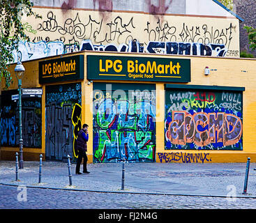 Berlin, Mann mit Handy in der Nähe von Rollos Store gehen und Gebäude mit Straßenkunst graffiti Stockfoto