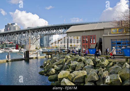 Felsige Küste am Granville Island Public Market und Granville Street Bridge am Wasser von False Creek. Winter Stockfoto