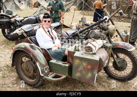 Zweiten Weltkrieg Re-enactment. Deutschen Motorrad Maschinengewehr und Seite Auto mit junge Rote hairrd Uniformierte deutsche Frau im Blick auf Viewer. Stockfoto