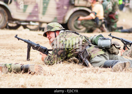 Swcond Weltkrieg Re-enactment. Deutsche Waffen-SS Soldaten in Dot camouflage Uniform, Verlegung in Gras, Holding MP40 sub Maschinengewehr während Scheingefecht. Stockfoto