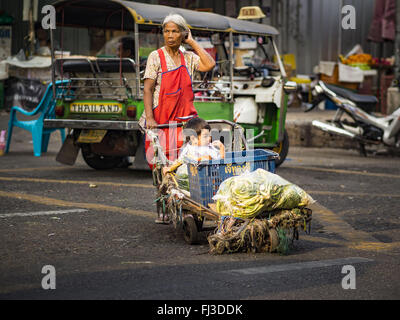 Bangkok, Bangkok, Thailand. 29. Februar 2016. Eine Frau kreuzt die Straße vor der Bangkok Blumenmarkt mit einem jungen in ihrer Familie. Viele der Bürgersteig Anbieter rund um Pak Khlong Talat, der Blumenmarkt Bangkok ihre Stände Montag geschlossen. Wie ein Teil der Militärregierung Initiative gesponserte, um Bangkok zu bereinigen, kündigte Stadtbeamte Neuregelung für den Bürgersteig-Anbietern, die ihre Arbeitszeit verkürzt und änderte die Vorschriften, mit denen sie unter gearbeitet. Einige Anbieter sagte, die neuen Regeln waren verwirrend und zu begrenzen und die meisten Anbieter wählte schließen Montag anstatt Gefahr Geldbußen und Strafe Stockfoto