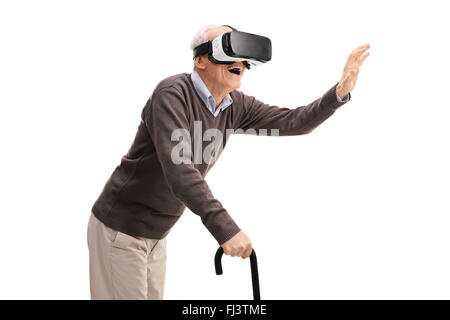 Ältere Gentleman mit einem Stock Spaß mit einem VR-Kopfhörer isoliert auf weißem Hintergrund Stockfoto