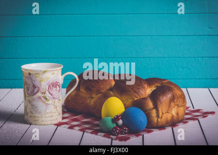 Bemalte Ostereier, leckeren Kuchen und Tasse Milch auf einem hölzernen Hintergrund. Umweltfreundliches Material ohne Gewalt gegen Tiere Stockfoto