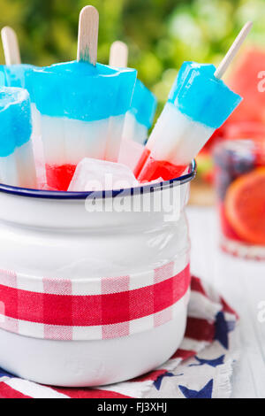 Hausgemachte rot-weiß-blauen Eis am Stiel auf einen Tisch im Freien mit erfrischenden Limonade im Hintergrund. Stockfoto