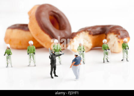 Winzige Polizei in Aufruhr Getriebe verhindert, dass einen übergewichtigen Mann erreicht Donuts eine öffentliche Gesundheit Adipositas Konzept Stockfoto