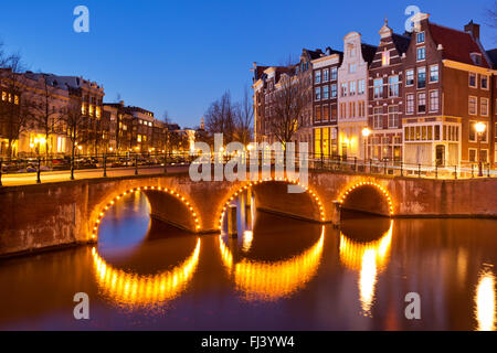 Eine Brücke über einen Kanal in der Stadt Amsterdam, die Niederlande in der Nacht. Stockfoto