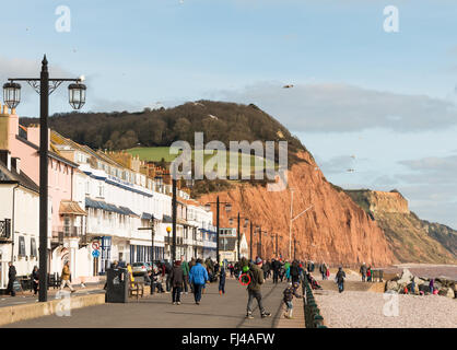 Blick auf Sidmouth Küste und Stadt mit Menschen zu Fuß am Strand mit Felsen im Hintergrund. Stockfoto