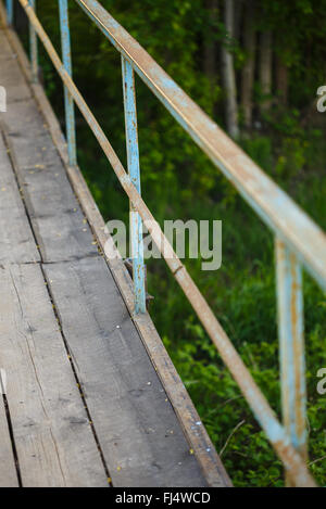 alte Brücke aus Holzbrettern mit rostigen Geländer Stockfoto