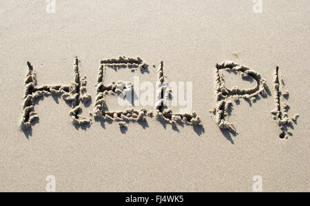 Hilfe geschrieben am Sandstrand Stockfoto