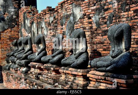 Ayutthaya, Thailand: Geschwärzten Überreste aus einer Reihe von Stein sitzenden Buddhas Futter einen Gehweg im Wat Chai Wattanaram Stockfoto