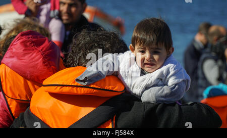 Lesbos, Griechenland - 13. Oktober 2015: Flüchtlingskind aus neu angekommenen Bootes aus der Türkei ans Ufer gezogen. Stockfoto