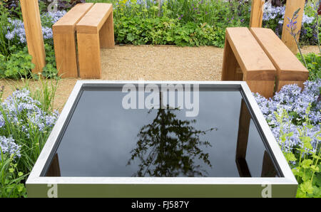 Kleiner Garten Teich Wasserspiel mit Holzbänken Sitzbereich Terrasse UK Stockfoto