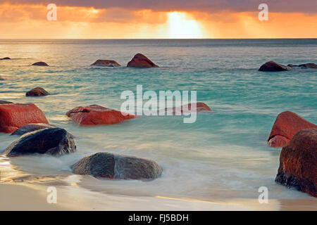 Granitfelsen in den Wellen der Anse Lazio bei Sonnenuntergang, Seychellen, Praslin Stockfoto