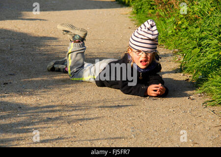 trotzige kleine Mädchen liegend auf einem Pfad Stockfoto