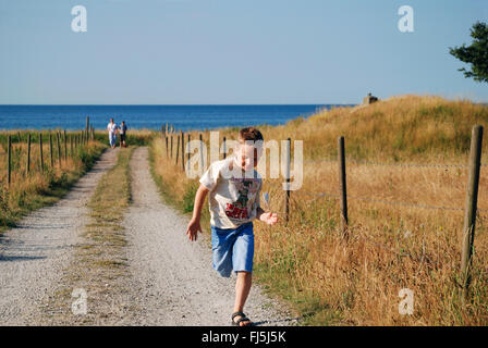 kleiner Junge läuft auf einem Feldweg an der Ostsee-Küste, Schweden Stockfoto