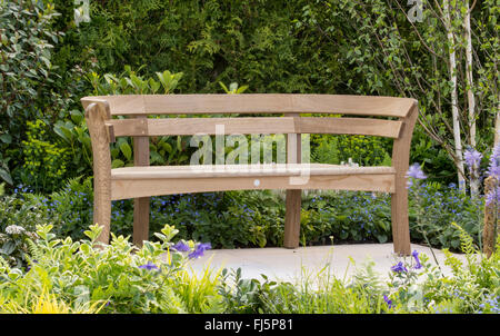 Kleiner Garten mit Sitzbereich eine Gartenbank aus Eichenholz, die von Blick Burvill auf einer gepflasterten Terrasse in der RHS Malvern Spring Show UK hergestellt wurde Stockfoto