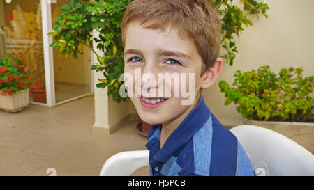 Junge sitzt auf einer Terrasse, Porträt Stockfoto