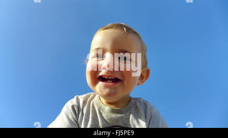 Kleinkind lachen vor blauem Himmel, Porträt eines Kindes Stockfoto