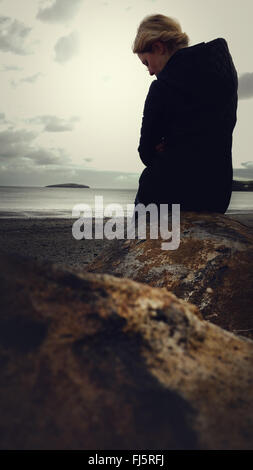 Frau am Strand von den Felsen stehend Stockfoto