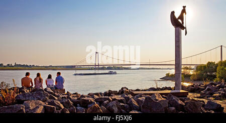 vier Personen in eine Skulptur am Rhein-Ufer, transportieren, Schiff und Brücke im Hintergrund, Deutschland, Nordrhein-Westfalen, Niederrhein, Emmerich Stockfoto