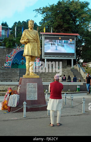 Leitender indischen Mann beobachtet ein Großbild-TV errichtet am Chowrasta (Hauptplatz), Darjeeling, Westbengalen, Indien. Stockfoto