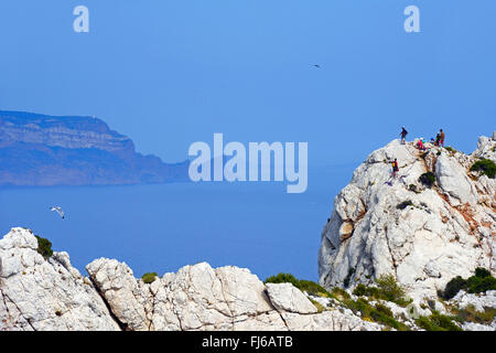 Kletterer auf dem küstennahen Felsen der Calanque de Sormiou, Cap de l'Aigle im Hintergrund, Frankreich, Calanques Nationalpark Stockfoto