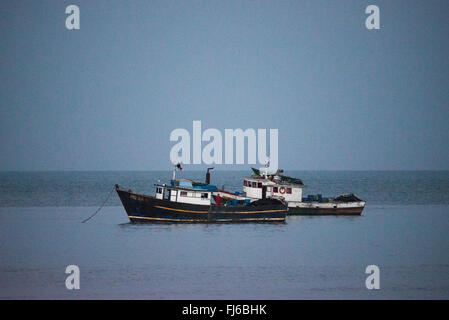 Holzfischboote Panama-Bucht Panama-Stadt Panama | PANAMA-STADT, Panama — Zwei Holzfischboote, eines namens "Posidon II" und mit der panamaischen Flagge, liegen vor Anker auf den ruhigen Gewässern der Panama-Bucht in der Dämmerung. Kleine Kutter wie diese versorgen immer noch die lokalen Fischmärkte, ein Lebensunterhalt, der die Hochhaus-Skyline, die nun am selben Ufer aufragt, vorausgeht. Die Panama-Bucht öffnet sich zum Golf von Panama, einer Bucht des Pazifischen Ozeans. Stockfoto