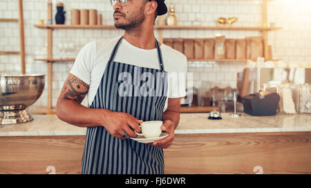 Zugeschnittenen Porträt junger Mann am Café Zähler stehen und wegsehen. Male auf arbeiten in Coffee-Shop. Stockfoto