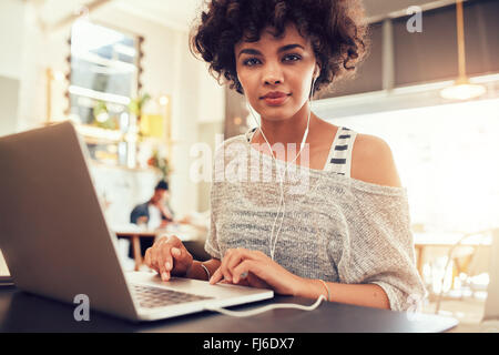 Porträt der jungen Frau mit Laptop im Café. Afrikanische Frau im Coffee-Shop mit einem Laptop. Stockfoto