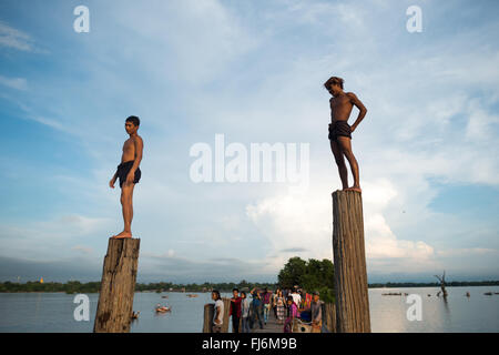 AMARAPURA, Myanmar – die U Bein Bridge erstreckt sich über den Taungthaman Lake bei Mandalay. Die 1,2 Kilometer lange Teakholzkonstruktion, die vermutlich die älteste und längste Teakholzbrücke der Welt ist, ist vom Himmel her umrahmt. Einheimische Fußgänger und Mönche überqueren die Brücke, während Touristen die berühmte Szene beobachten, die besonders bei Sonnenuntergang beliebt ist. Stockfoto